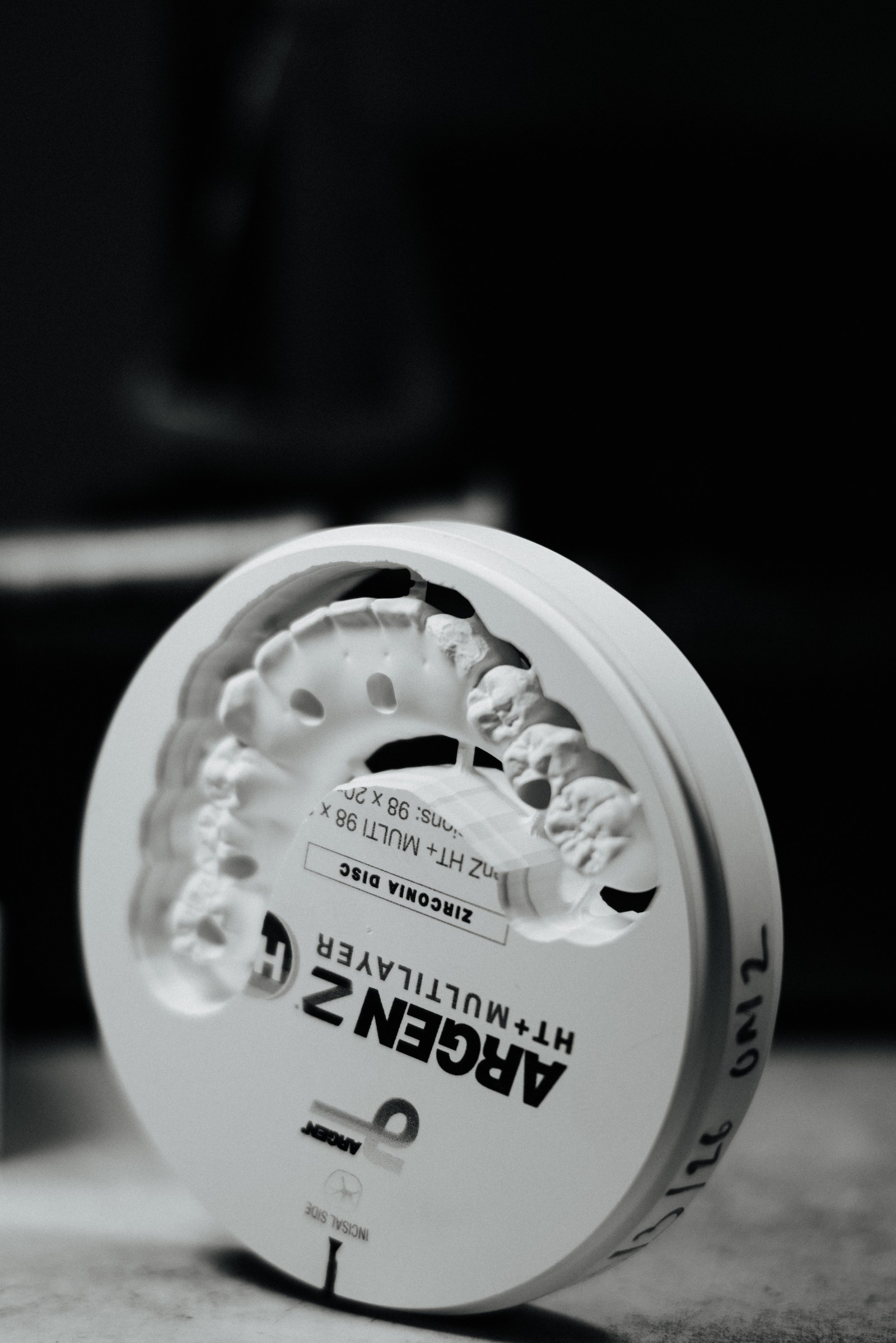 Multilayer zirconia milling disc photographed at an angle, shade gradient visible through the puck