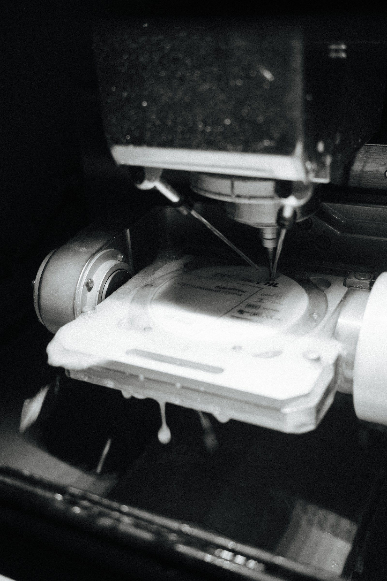 Multilayer zirconia disc being wet milled, coolant streaming across the chamber