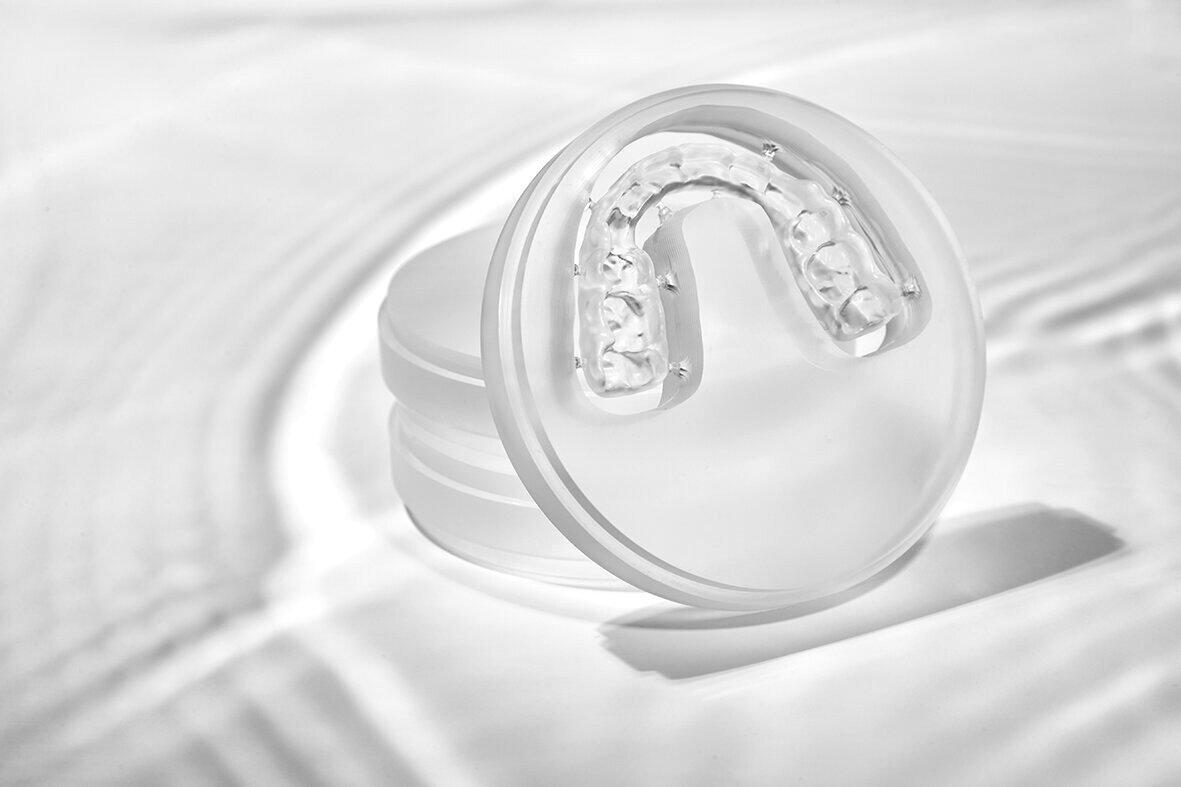 Clear occlusal splint with water droplets on a bright surface