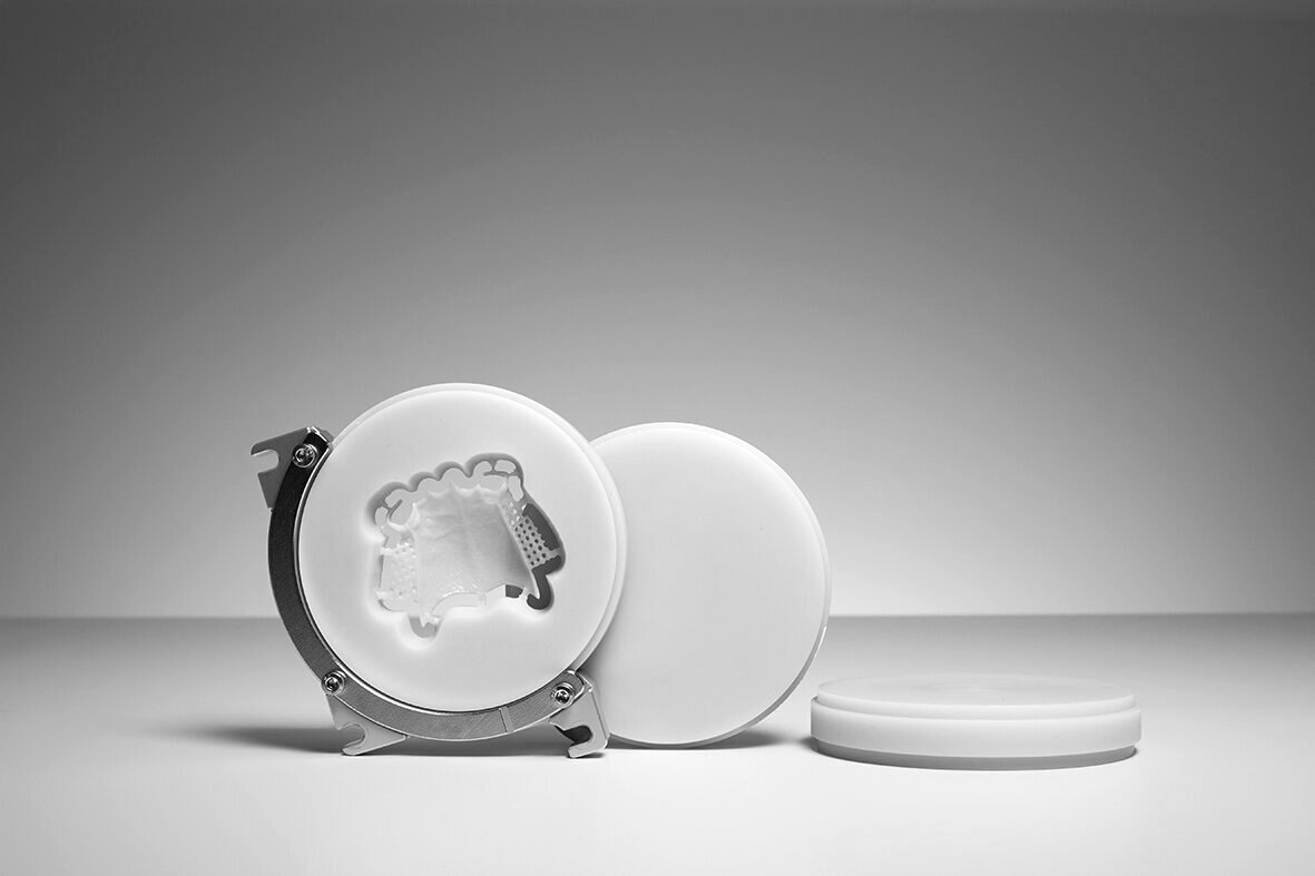 Full-arch provisional milled from a PMMA disc, still in the puck