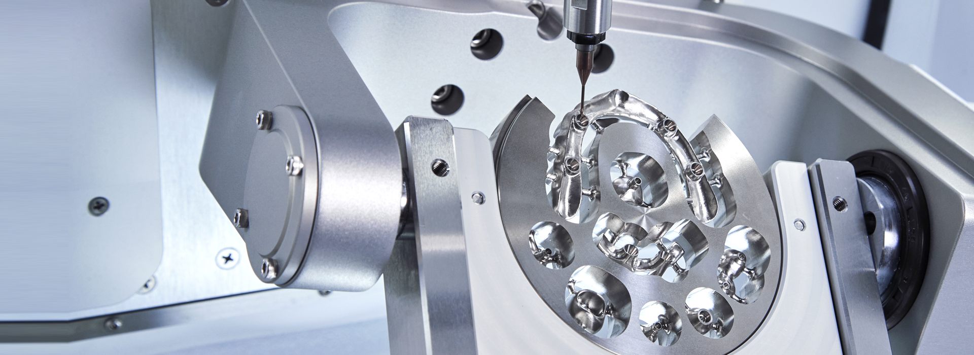 Inside the ARUM A5 Pro chamber, milling titanium abutments and a bar from a disc