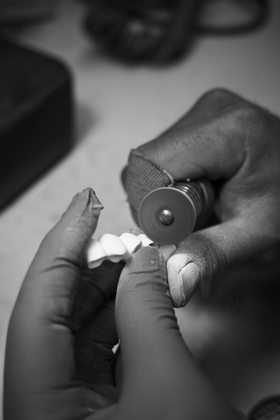 A technician hand-finishing a restoration at the laboratory bench